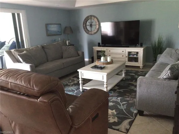 a living room with furniture a flat screen tv and a window
