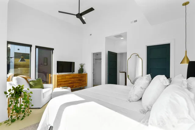 a bedroom with a bed a large window and potted plant on the dresser