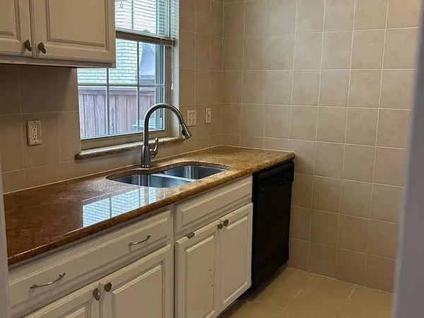 a close view of a sink and dishwasher with a window