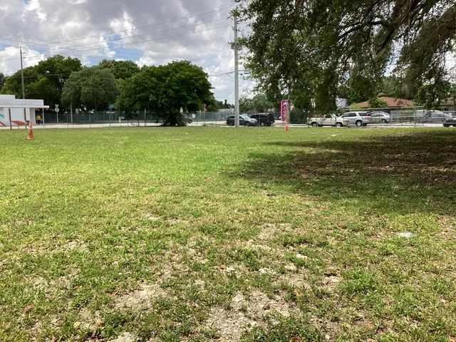 a view of a field with of trees in the background