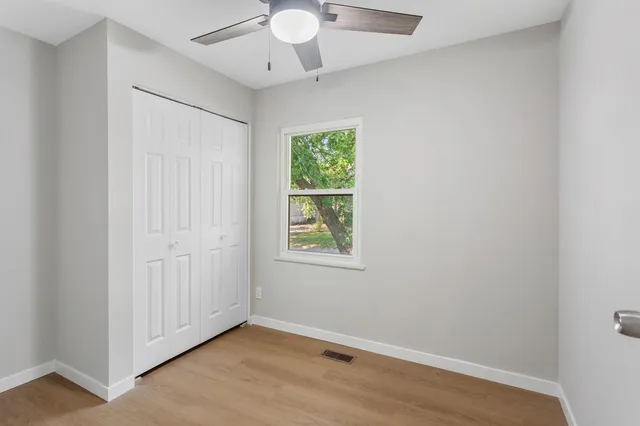 an empty room with a window and a ceiling fan