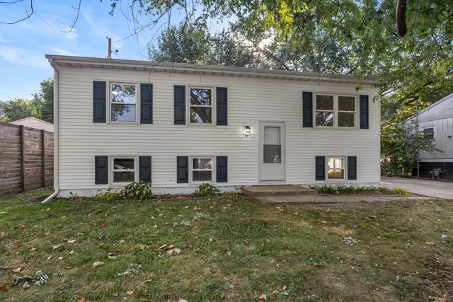 a front view of house with yard and trees in the background