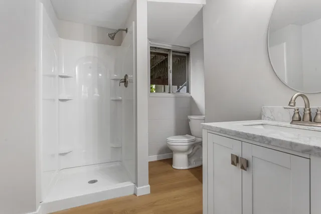 a bathroom with a granite countertop sink a toilet and shower