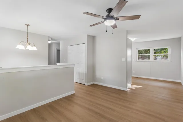 a view of an empty room with wooden floor and a ceiling fan