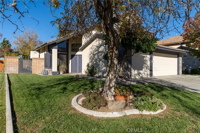 a backyard of a house with fountain plants and large tree