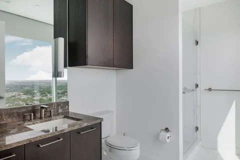 a bathroom with a granite countertop sink a toilet and a mirror