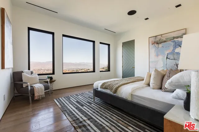 a spacious bedroom with a bed and wooden floor