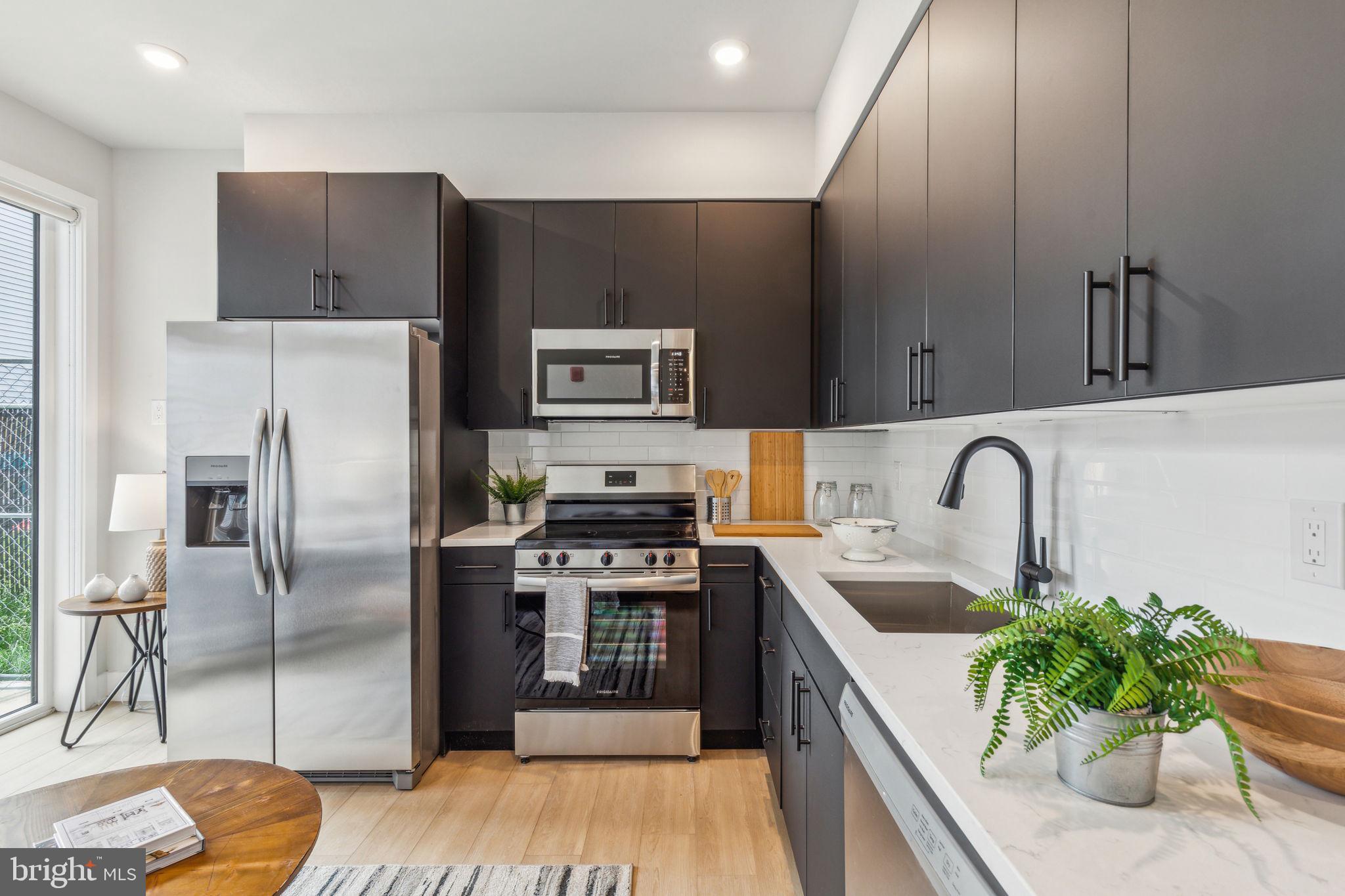 6910 Ridge Avenue, Unit 116 Philadelphia, PA 19128 - Photo 6 of 23 a kitchen with stainless steel appliances kitchen island granite countertop a refrigerator a sink a stove with wooden cabinets