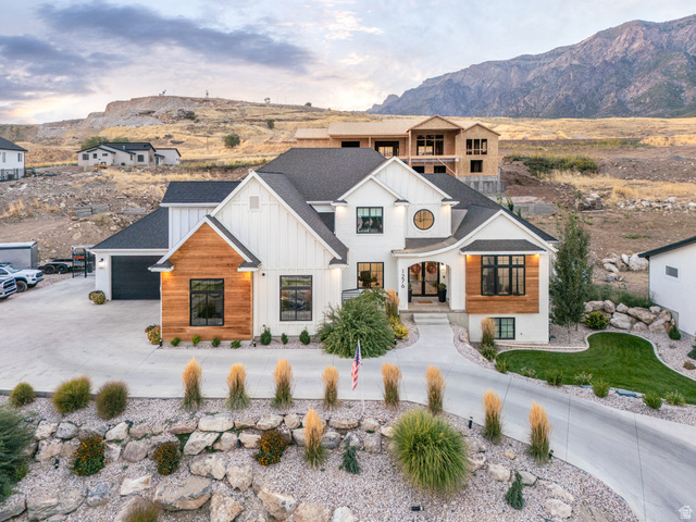 1276 West Fallow Way, Unit 76 Ogden, UT 84414 - Photo 2 of 22 View of front of house featuring curved driveway, a shingled roof, board and batten siding, a mountain view, and an attached garage