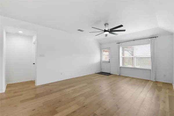 a view of empty room with wooden floor and fan