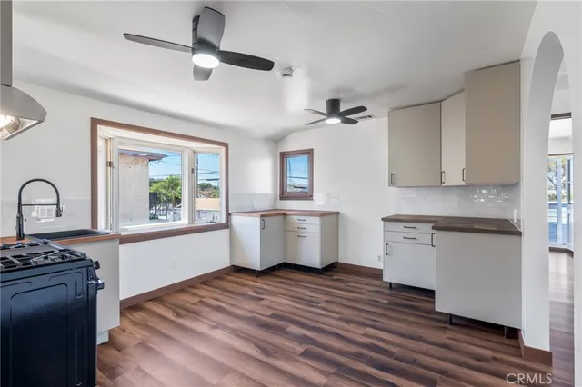 a kitchen with stainless steel appliances granite countertop a stove a sink dishwasher a refrigerator and white cabinets with wooden floor