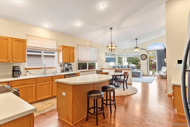 a kitchen with stainless steel appliances granite countertop a table chairs stove and wooden floor