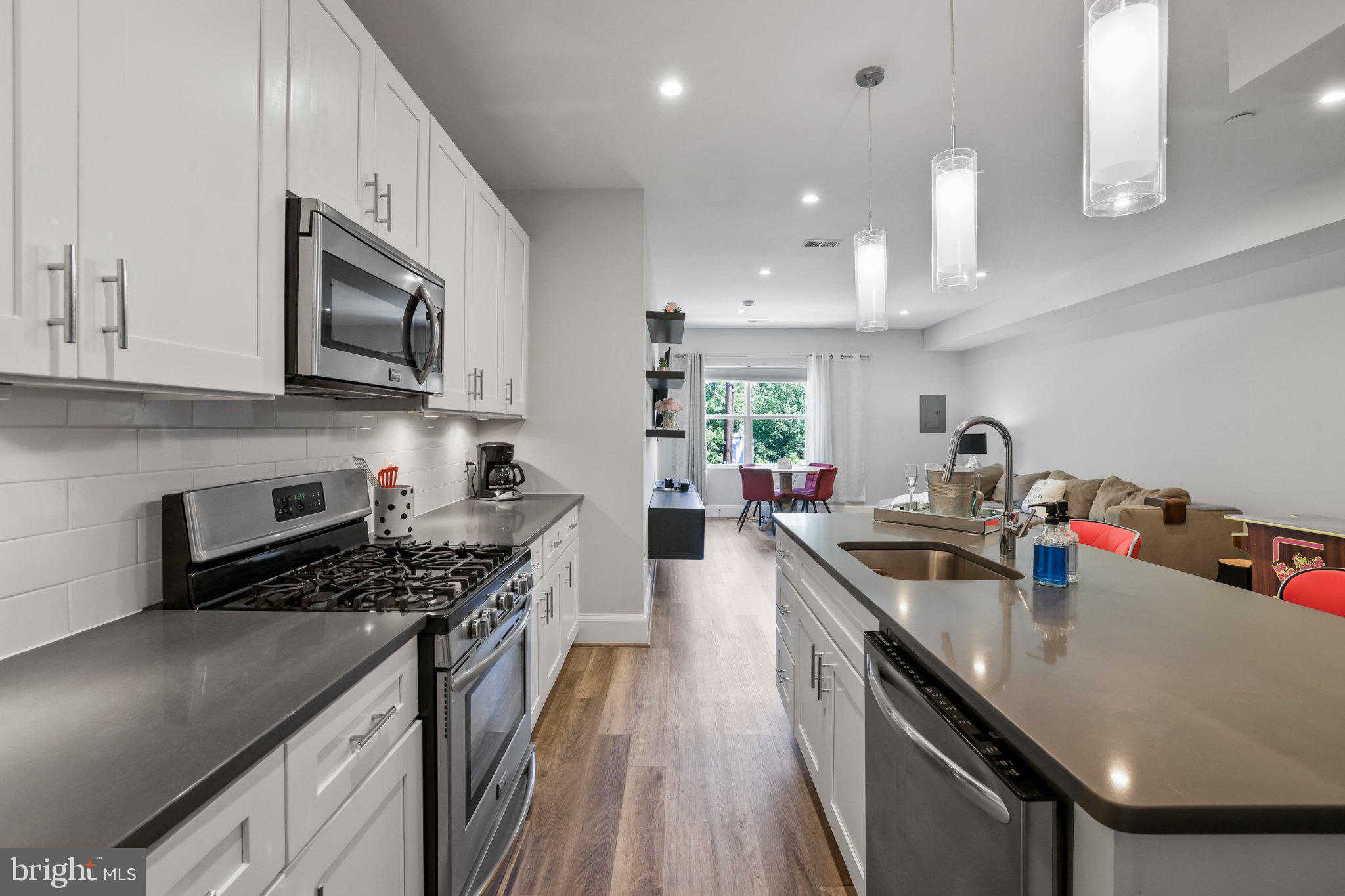 2221 M Street Northeast, Unit PH1 Washington, DC 20002 - Photo 20 of 38 a kitchen with kitchen island granite countertop a sink a stove and wooden cabinets