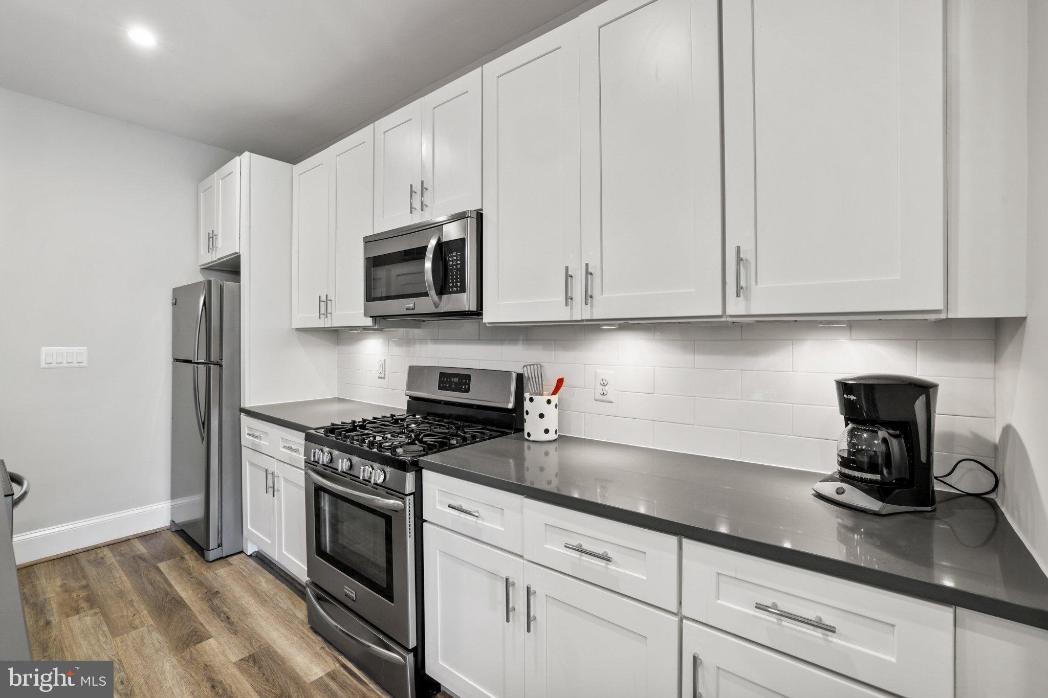 2221 M Street Northeast, Unit PH1 Washington, DC 20002 - Photo 22 of 38 a kitchen with granite countertop white cabinets and stainless steel appliances