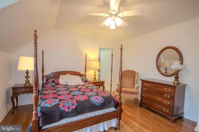 a bedroom with a bed a mirror on dresser and a chandelier