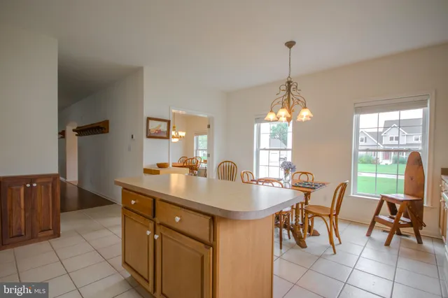 a dining hall with stainless steel appliances granite countertop a sink a stove a dining table and chairs