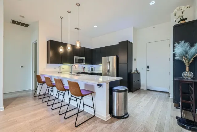 a kitchen with stainless steel appliances a dining table chairs refrigerator and microwave