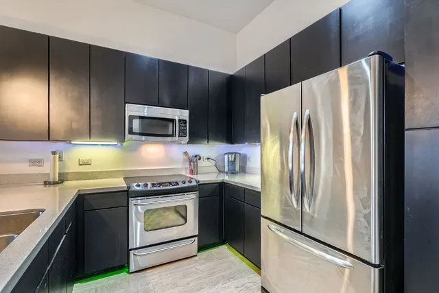 a kitchen with granite countertop a refrigerator stove and microwave