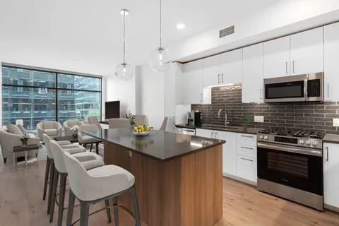 a kitchen with stainless steel appliances a stove a sink a microwave a dining table and chairs