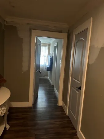 a view of a hallway with wooden floor and a bathroom
