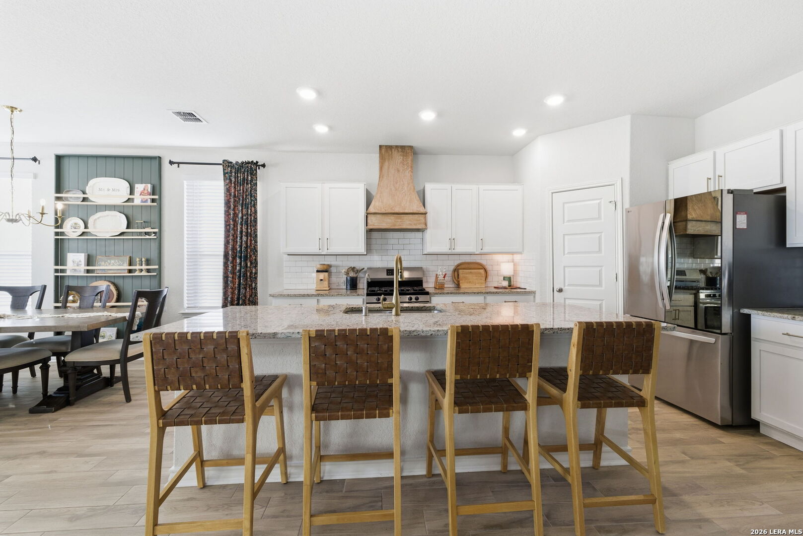 3410 Copper Acres Bulverde, TX 78163 - Photo 14 of 50 a kitchen with stainless steel appliances kitchen island granite countertop a dining table chairs refrigerator and sink