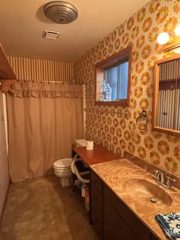 a bathroom with a granite countertop sink and a toilet