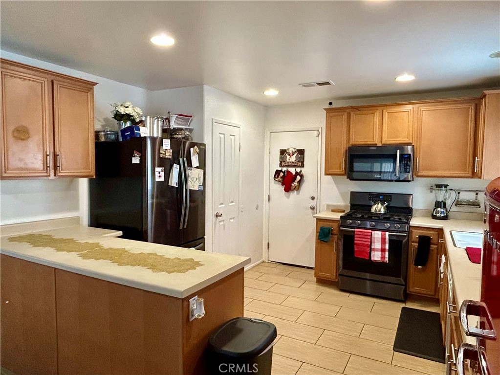 567 Botan Street Perris, CA 92571 - Photo 13 of 38 a kitchen with a refrigerator and a stove top oven