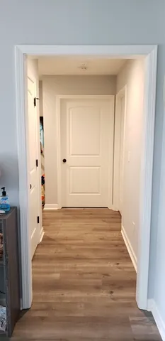 a view of an empty room with wooden floor and a bathroom
