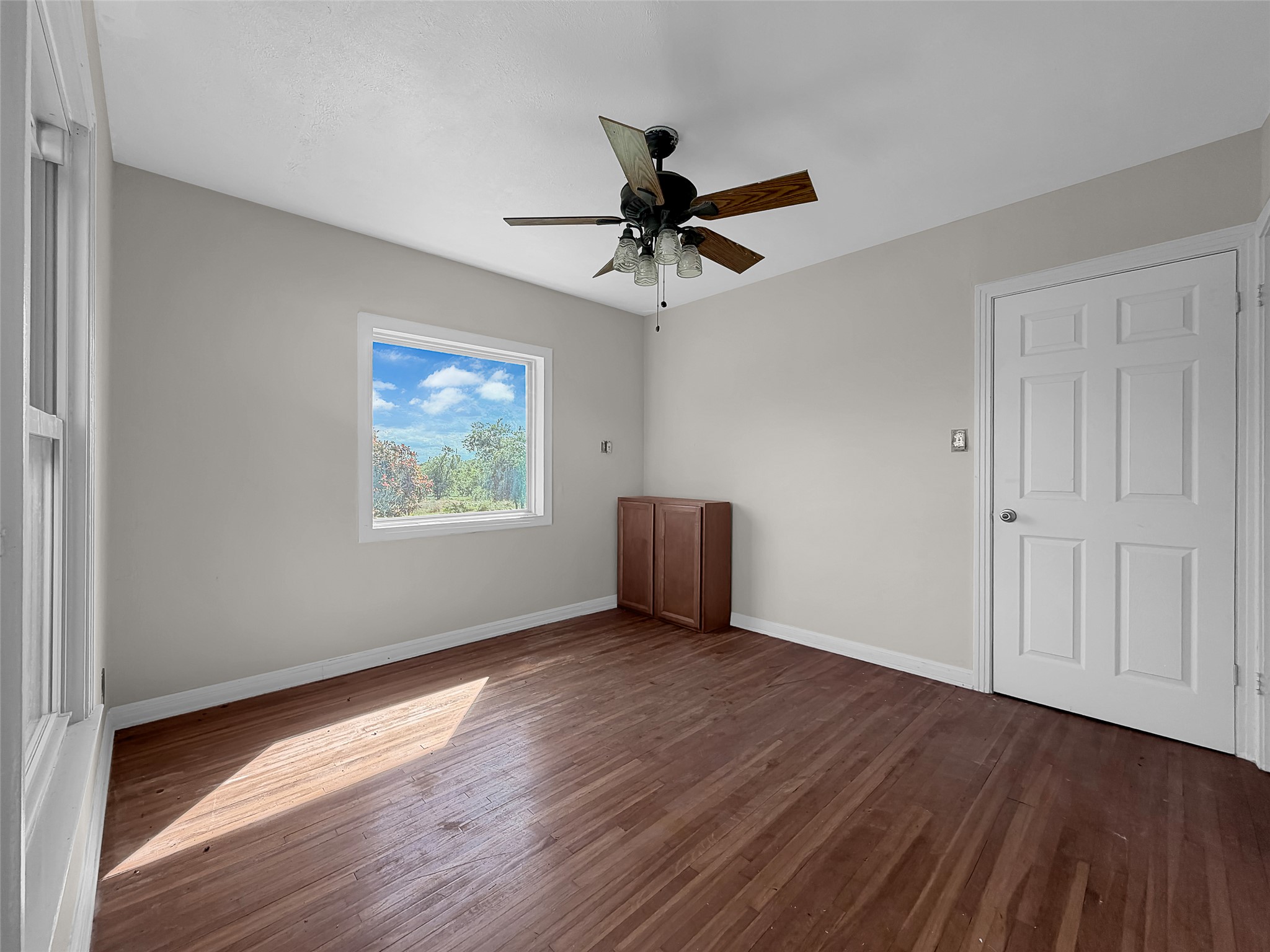 925 Long Hollow Road Dale, TX 78616 - Photo 18 of 26 Room featuring wood-finish flooring, a ceiling fan with light fixture, and a built-in wood-finish cabinet