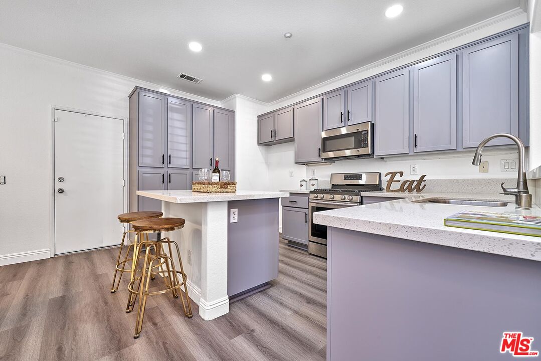 38 Windward Way Buena Park, CA 90621 - Photo 12 of 71 a kitchen with stainless steel appliances granite countertop a sink a stove a refrigerator cabinets and a dining table with wooden floor