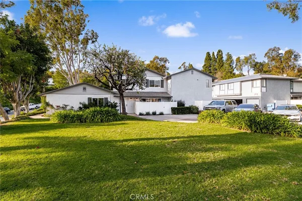 a front view of a house with a big yard and potted plants