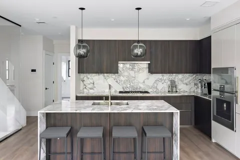 a kitchen with kitchen island stainless steel appliances a table chairs sink and stove top oven