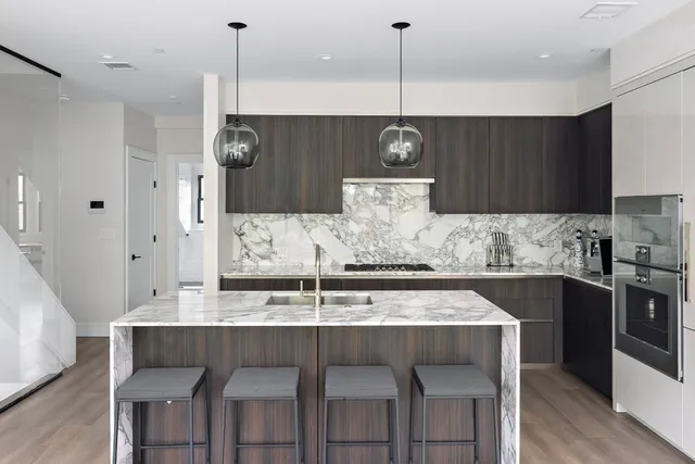 a kitchen with kitchen island stainless steel appliances a table chairs sink and stove top oven