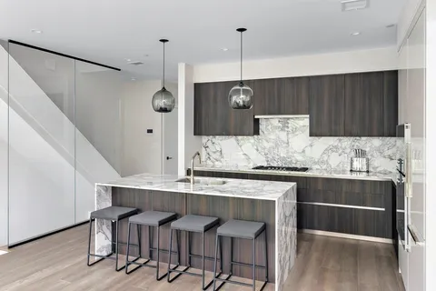 a kitchen with kitchen island granite countertop a table chairs sink and cabinets