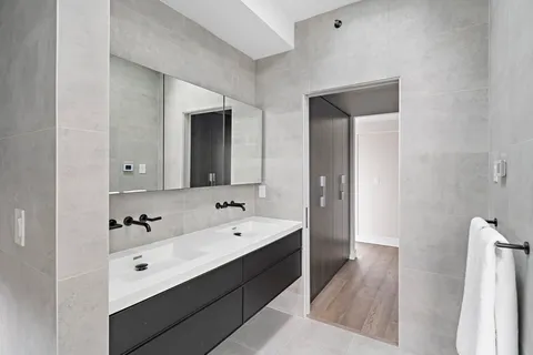 a en suite bathroom with a double vanity sink a mirror and a bathtub