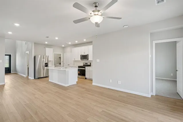 a living room with furniture kitchen view and a wooden floor