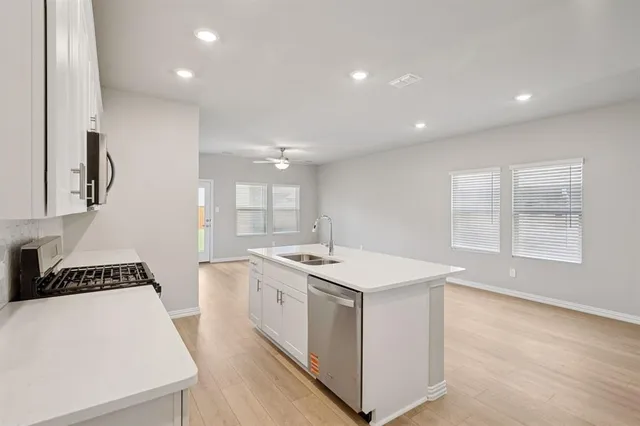 a kitchen with stainless steel appliances kitchen island granite countertop a sink a stove a refrigerator cabinets and a counter top space