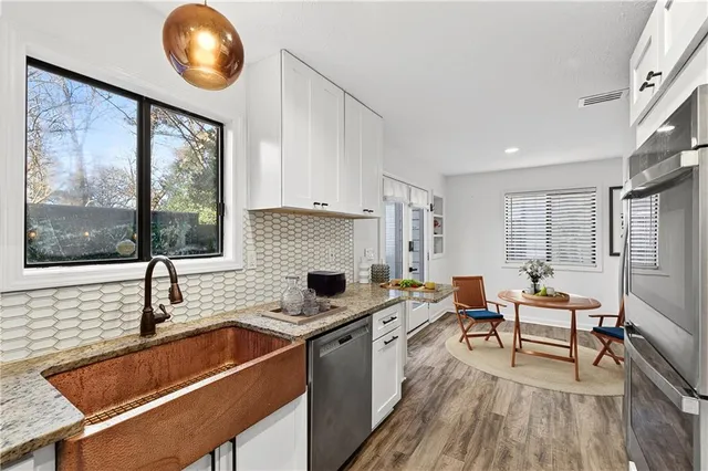 a kitchen that has a sink and a stove with wooden floors