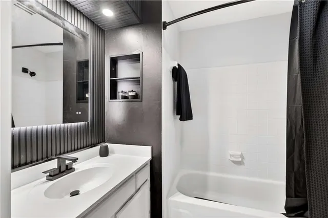 a bathroom with a tub sink vanity and mirror