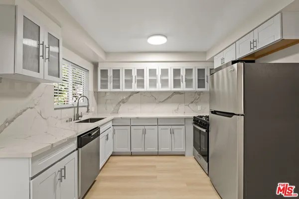 a kitchen with granite countertop a sink stove and refrigerator