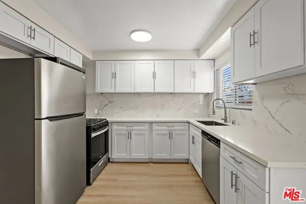 a kitchen with a sink a refrigerator and white cabinets