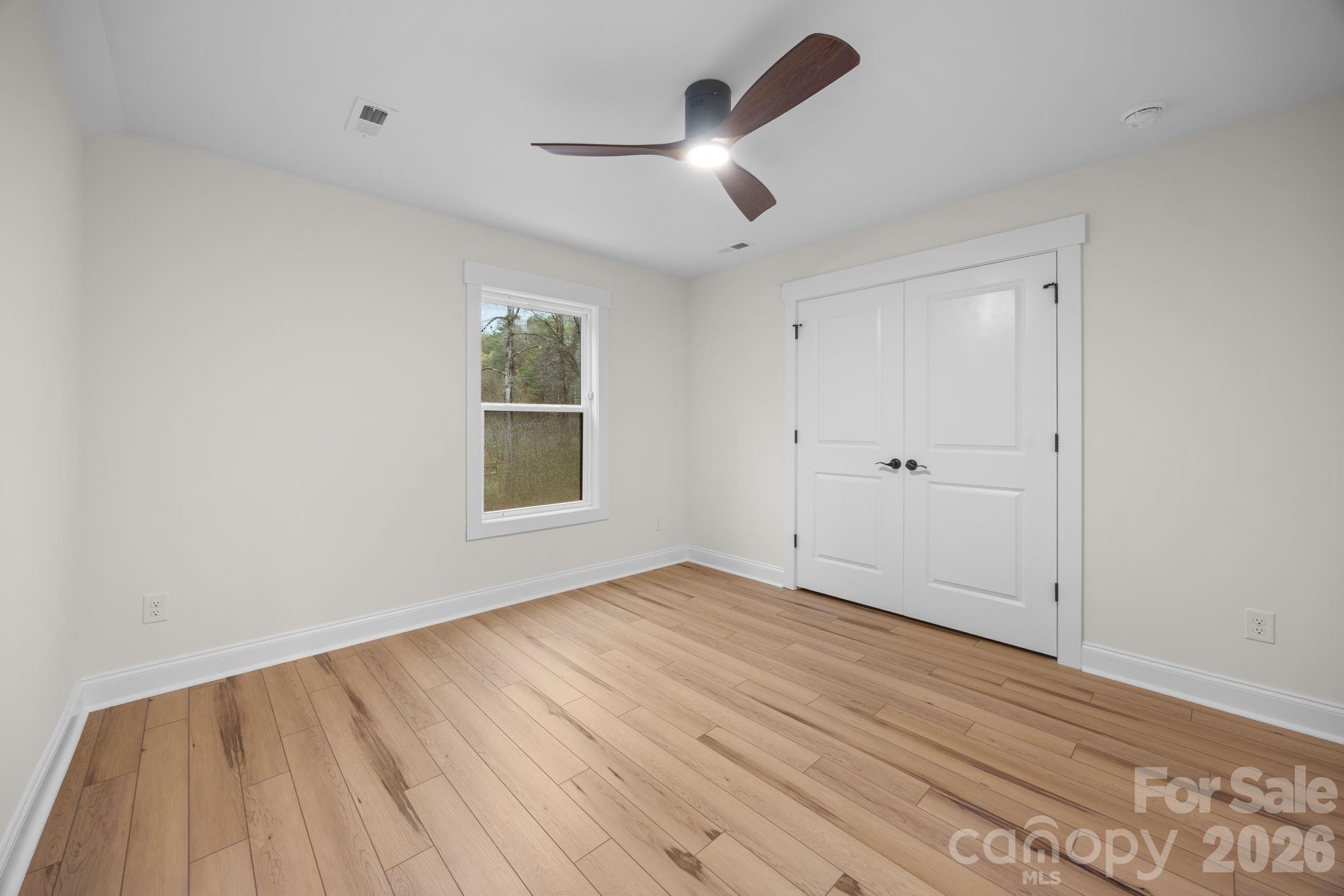 635 Fiber Acres A Street Cleveland, NC 27013 - Photo 32 of 42 an empty room with wooden floor chandelier fan and windows