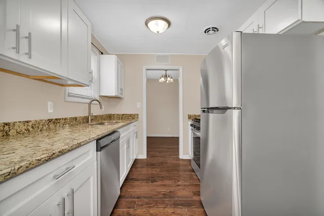 a bathroom with granite countertop a sink and a refrigerator