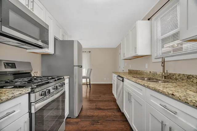 a kitchen with stainless steel appliances granite countertop a stove a sink and a microwave