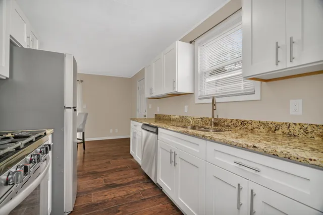 a kitchen with granite countertop a sink stove and refrigerator