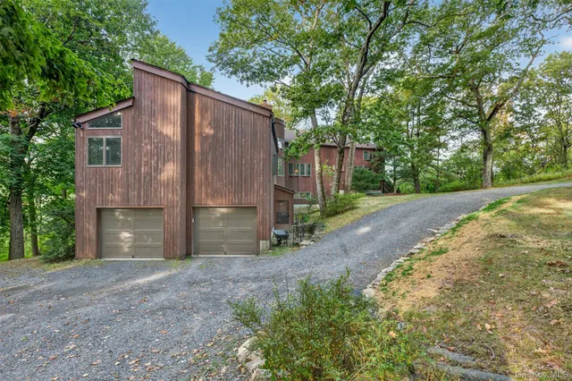 an aerial view of a house with a yard and covered with trees