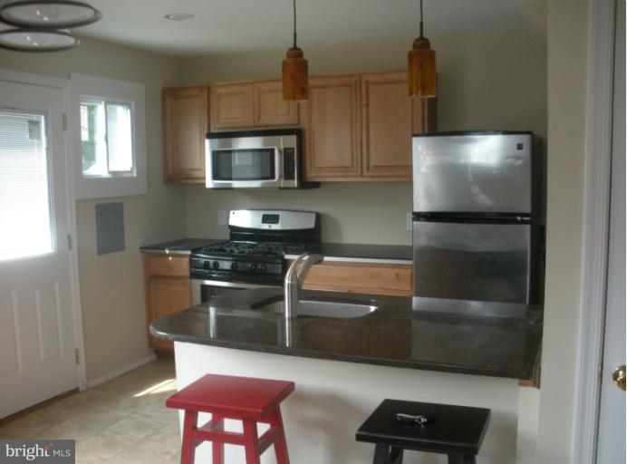 12008 Bluhill Road Silver Spring, MD 20902 - Photo 2 of 5 a kitchen with stainless steel appliances a stove a microwave and a refrigerator