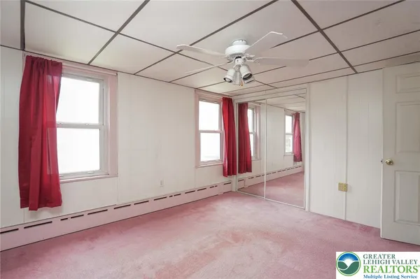 an empty room with windows and fan