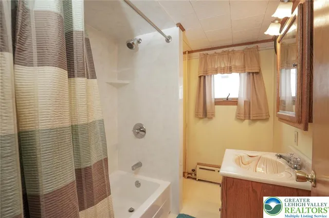 a bathroom with a tub shower vanity and a sink