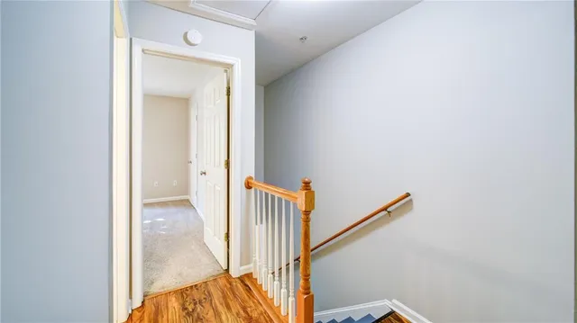 a view of a hallway with wooden floor and a bathroom